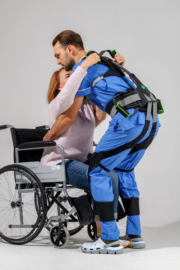 Exoskelett Hunic CareExo Lift - Pfleger hebt Frau aus Rollstuhl